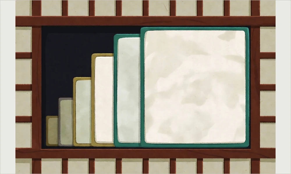 Six shell tiles of graduated widths laid in a wooden tray in descending order, the widest edged green and the narrowest edged brass, with one recess left empty.